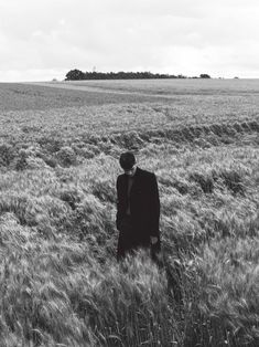 a man in a suit and tie standing in tall grass