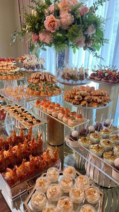 an assortment of pastries and desserts on display at a buffet table with flowers in the background