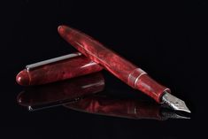 two red pens sitting next to each other on top of a black surface with reflection