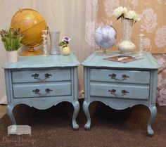 two blue nightstands with flowers and vases on them sitting next to each other