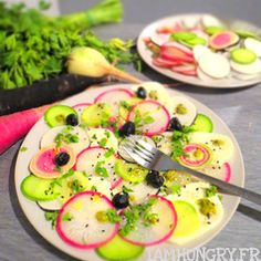 two plates filled with food sitting on top of a table next to radishes and broccoli