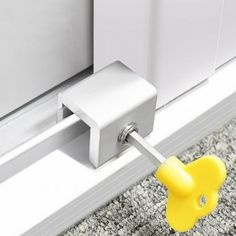 a yellow push button is attached to the side of a white door handle on a gray carpeted floor