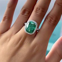 a woman's hand with an emerald and diamond ring