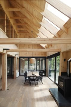 a large open room with wooden walls and flooring is furnished with black chairs and tables