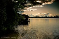 the sun is setting over the water and clouds are in the sky above it,