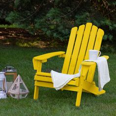 a yellow lawn chair sitting on top of a lush green field next to a lantern