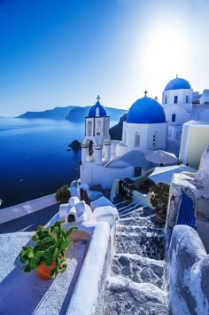 the sun shines brightly over an island with white buildings and blue domes on it