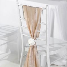 a white chair with a rose on the back of it and a table cloth draped over it