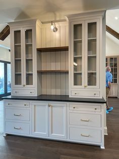 a large kitchen with white cabinets and black counter tops in an open floor plan area