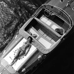 a woman laying on top of a boat in the water