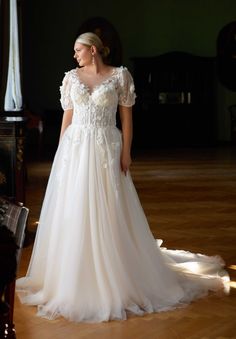 a woman in a white wedding dress standing on a wooden floor next to a piano