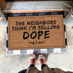 someone standing in front of a door mat that says the neighbors think i'm selling dope