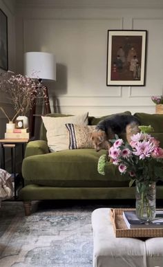 a living room with green couches and flowers in vases on the coffee table