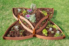 a wooden planter filled with lots of different types of flowers and plants on top of grass