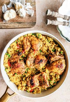 chicken and rice in a white bowl next to garlic