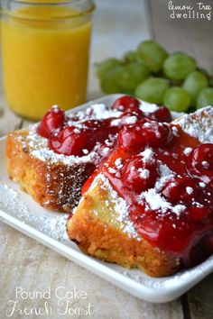 two pieces of french toast on a plate with fruit and powdered sugar next to it