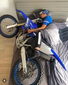 a man laying on top of a bed next to a dirt bike in a room