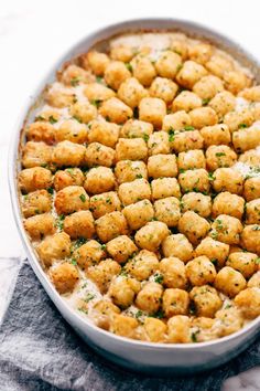 a pan filled with tater tots on top of a table next to a napkin