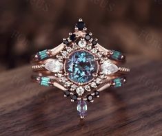 a fancy ring with an aqua blue stone surrounded by white and black diamonds on a wooden surface