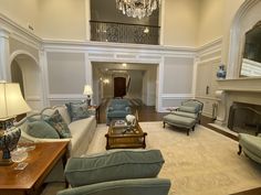 a living room filled with lots of furniture and a chandelier hanging from the ceiling