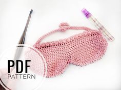 a crocheted pink purse next to a pair of scissors and thread on a white surface