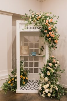 an old fashioned phone booth with flowers and greenery on the front, along with other decorations