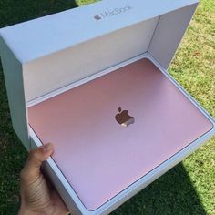 someone holding an apple laptop in their hand and it's inside the box that is open