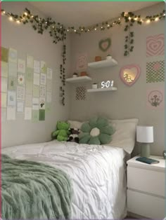 a bedroom decorated in pastel green and white with string lights strung from the ceiling