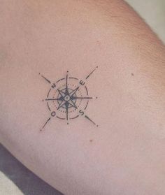 a small compass tattoo on the arm