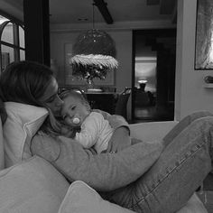 a woman sitting on a couch holding a baby in her lap and kissing her cheek