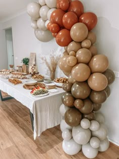 a table topped with lots of balloons next to a white and brown table cloth covered in food