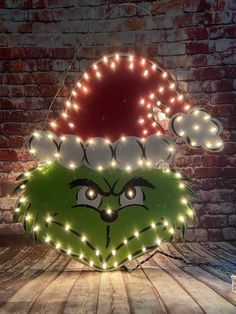 the grin face has been decorated with christmas lights and is sitting in front of a brick wall