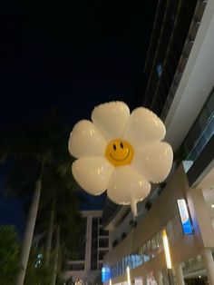 a large white flower with a smiley face on it's head hanging from the ceiling