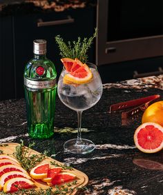 grapefruit, orange slices and rosemary garnish sit on a marble counter top