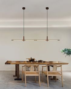 a dining room table with four chairs and two lights hanging from the ceiling above it