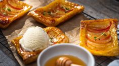 four pieces of bread with fruit and ice cream on top sitting on a wooden table