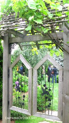 a wooden arbor with metal trelliss and flowers in the center is surrounded by greenery