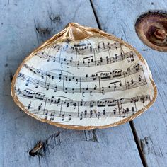 a ceramic dish with sheet music on it sitting on top of a wooden table next to a piece of wood