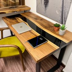 a laptop computer sitting on top of a wooden desk next to a potted plant