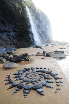 rocks arranged in the shape of a star on a beach near a waterfall with water coming from it