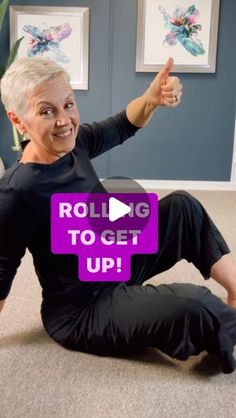 an older woman sitting on the floor with her thumbs up