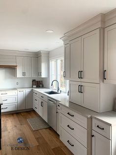 an empty kitchen with white cabinets and wood floors