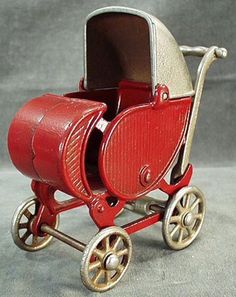 a red toy baby carriage with wheels on a gray background, it appears to be used as a child's toys