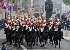 a large group of people riding on the backs of black horses down a city street