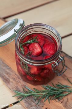 a jar filled with strawberries sitting on top of a wooden table