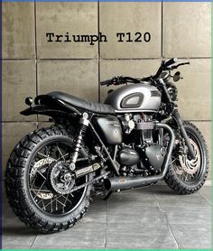 a motorcycle parked next to a wall with the words triumph t120 on it