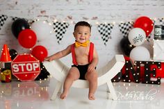 a baby boy sitting on a chair in front of balloons and decorations for his first birthday