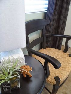 a chair with a plant on it next to a lamp and a small potted plant