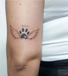 a woman's arm with a paw and angel wings tattoo on the left side