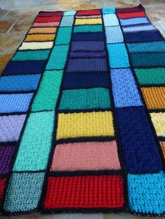 a multicolored crocheted blanket is laying on the floor